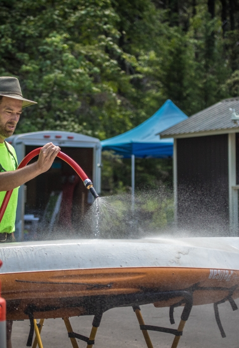 A person sprays off the bottom of a boat.