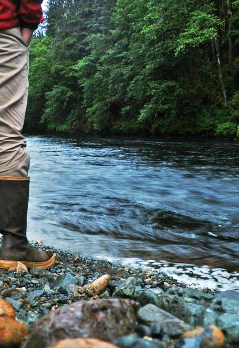 man standing by a river in rain gear