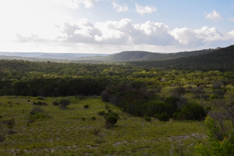 A landscape of grasslands in the foreground and rolling hills in the distance